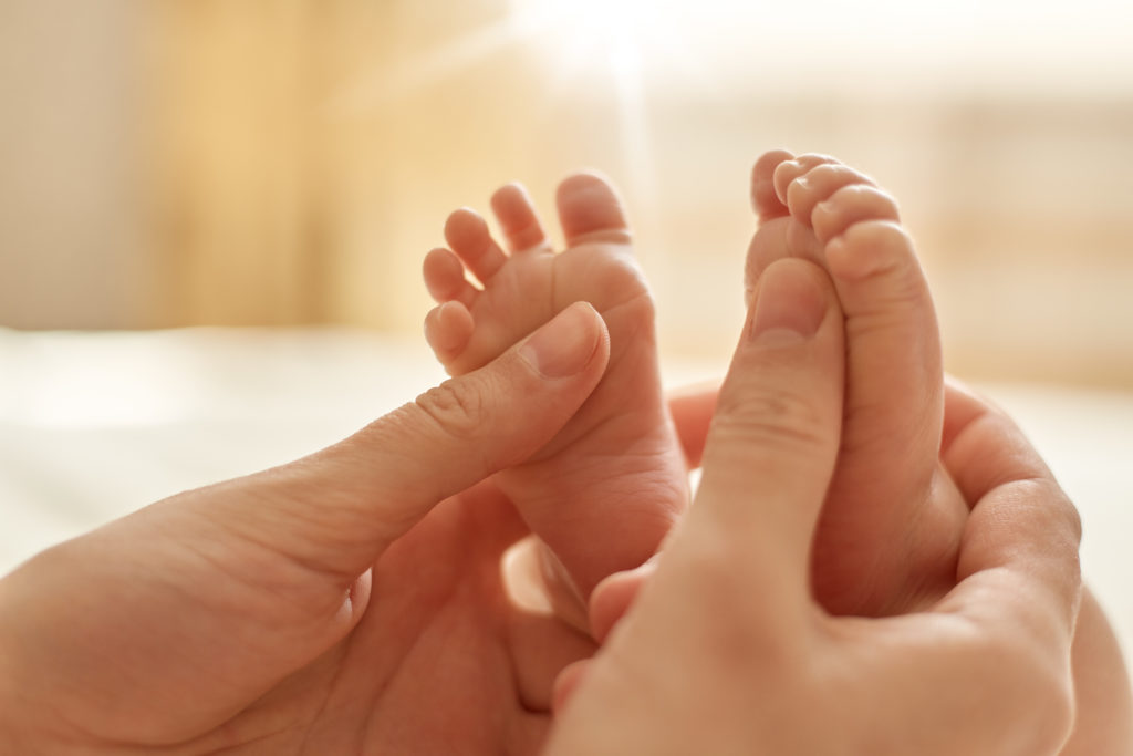 mains de maman câlinant les petits pieds de bébé