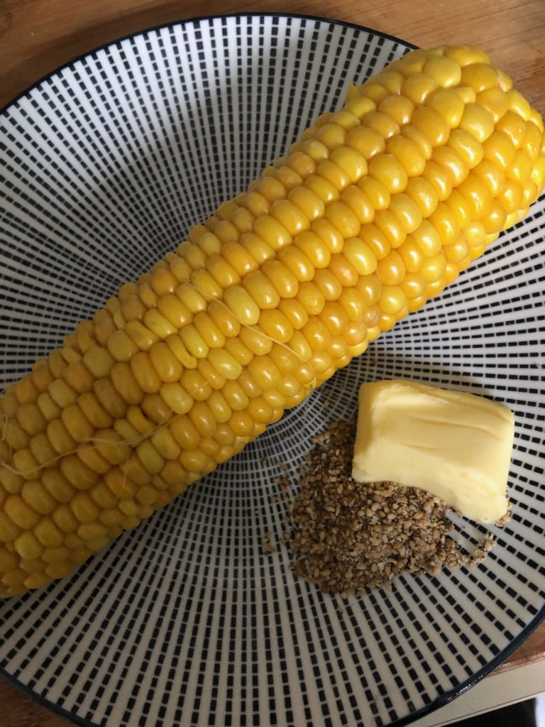 Épi de maïs, beurre et gomasio sur une assiette bon pour l'hygiène de vie du sportif